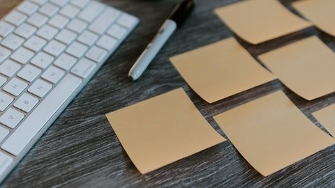 sticky notes, a pen and a keyboard on a desk 