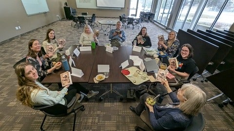 people gathered around a table holding a book 