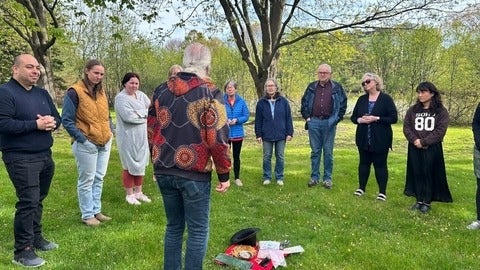 grad students stand outside, listening to Terry speak