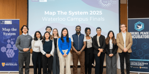 Group of student finalists stand in front of the 2025 finalist competition screen, having just presented.