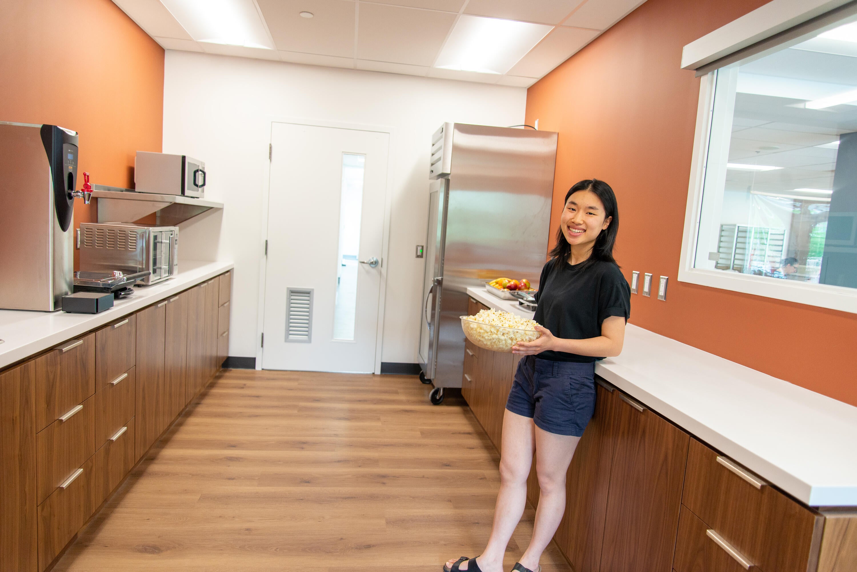 a student hold a bowl of popcorn in the new pantry area for residents and associates