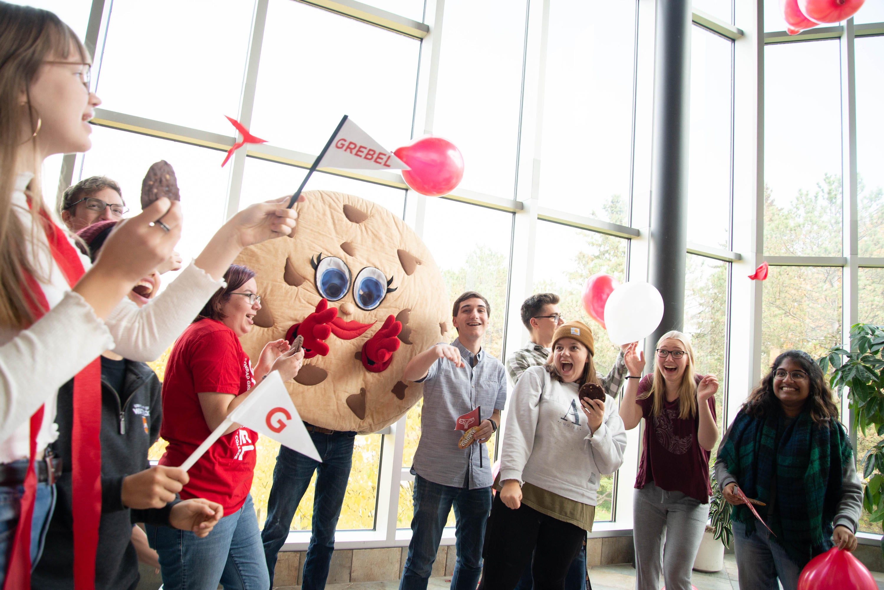 Picture of grebelites who are holding cookies and are dancing with the cookie mascot