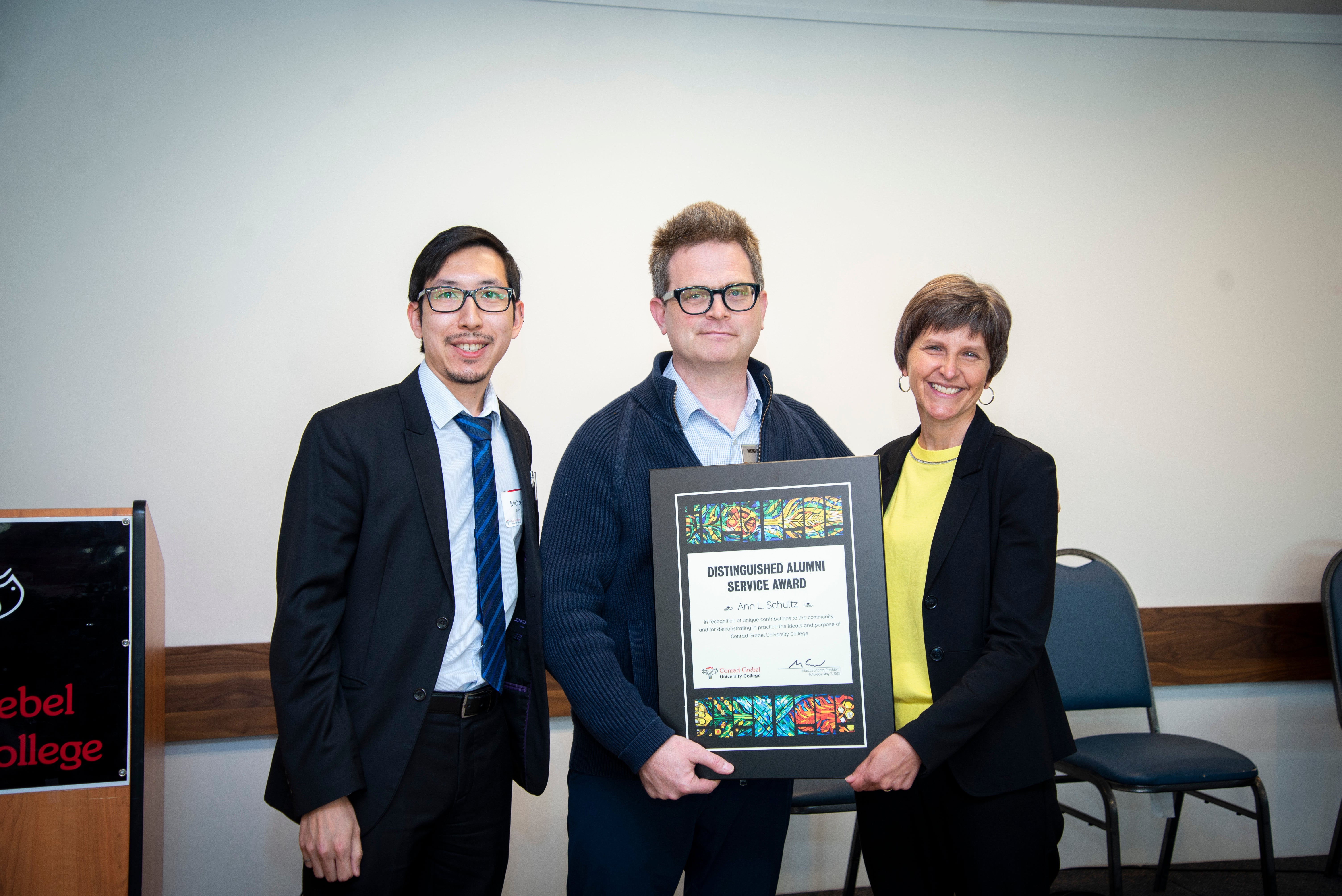 Ann recieves the distinguished alumni award plaque from President Marcus Shantz and Micheal Shum, Alumni board rep.
