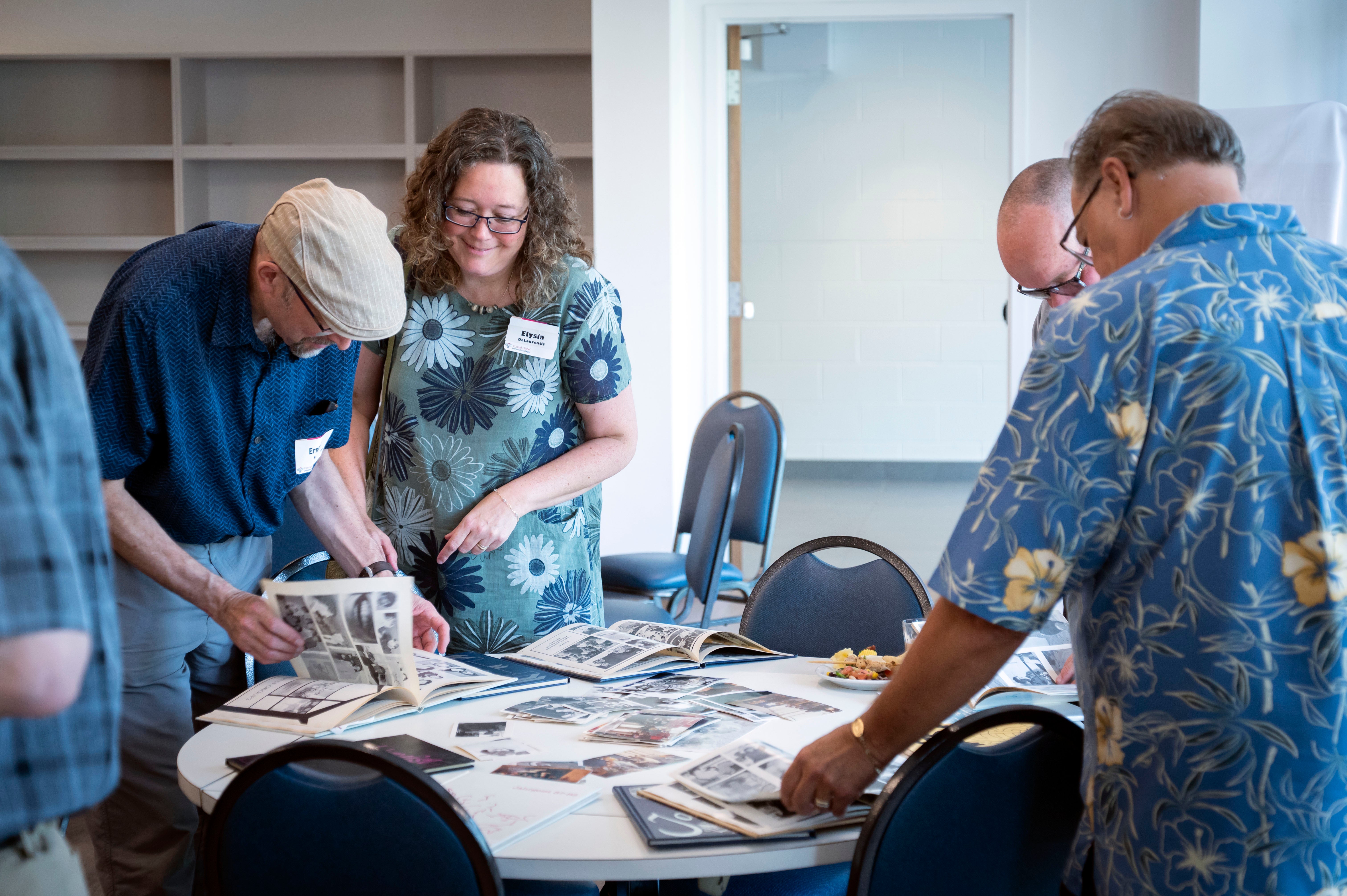 Alumni look at Grebel yearbooks on one of the dining room tables