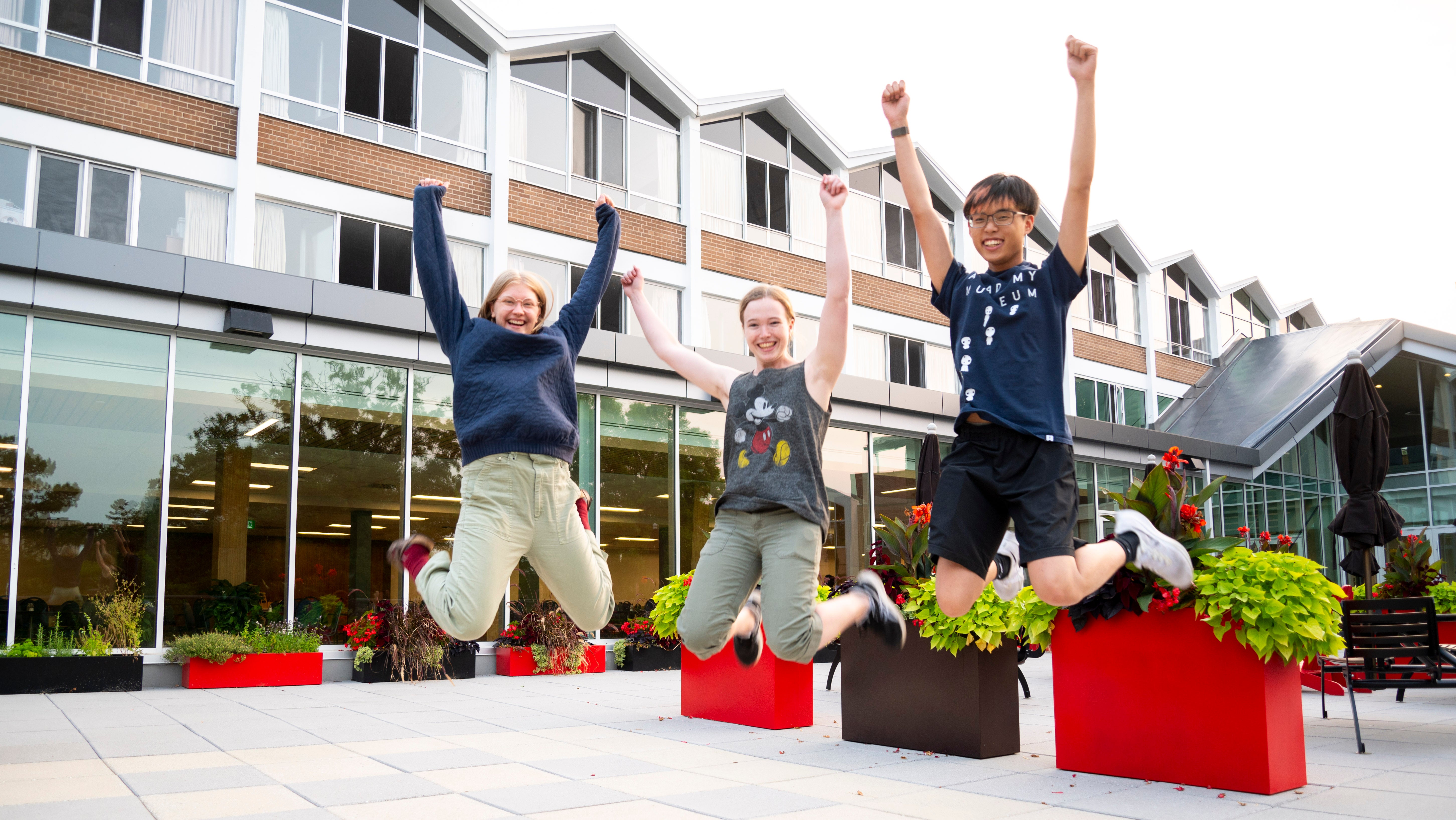 3 students mid jump; Ella is on the left