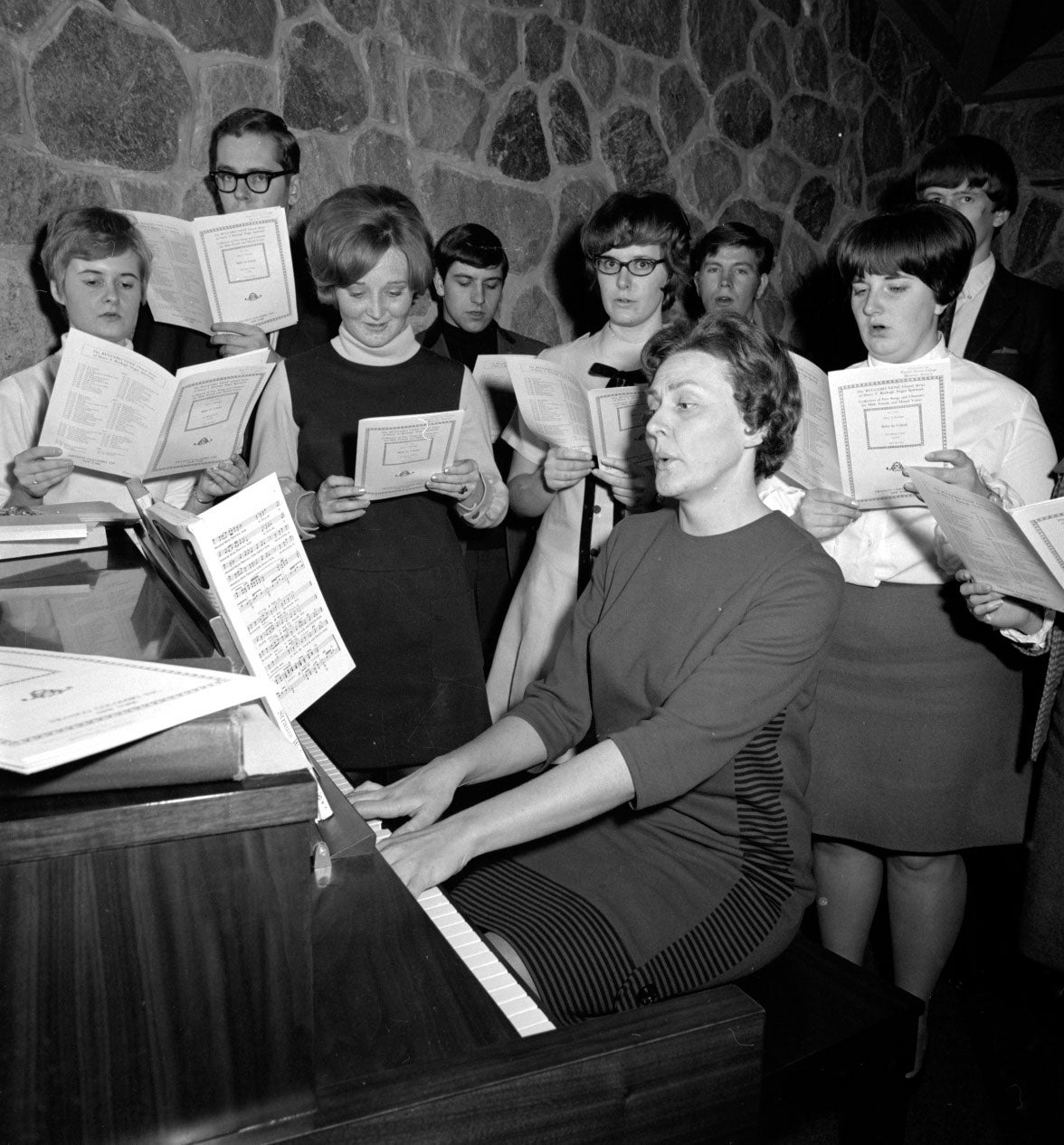 Helen Martens playing Piano with chior group behind her