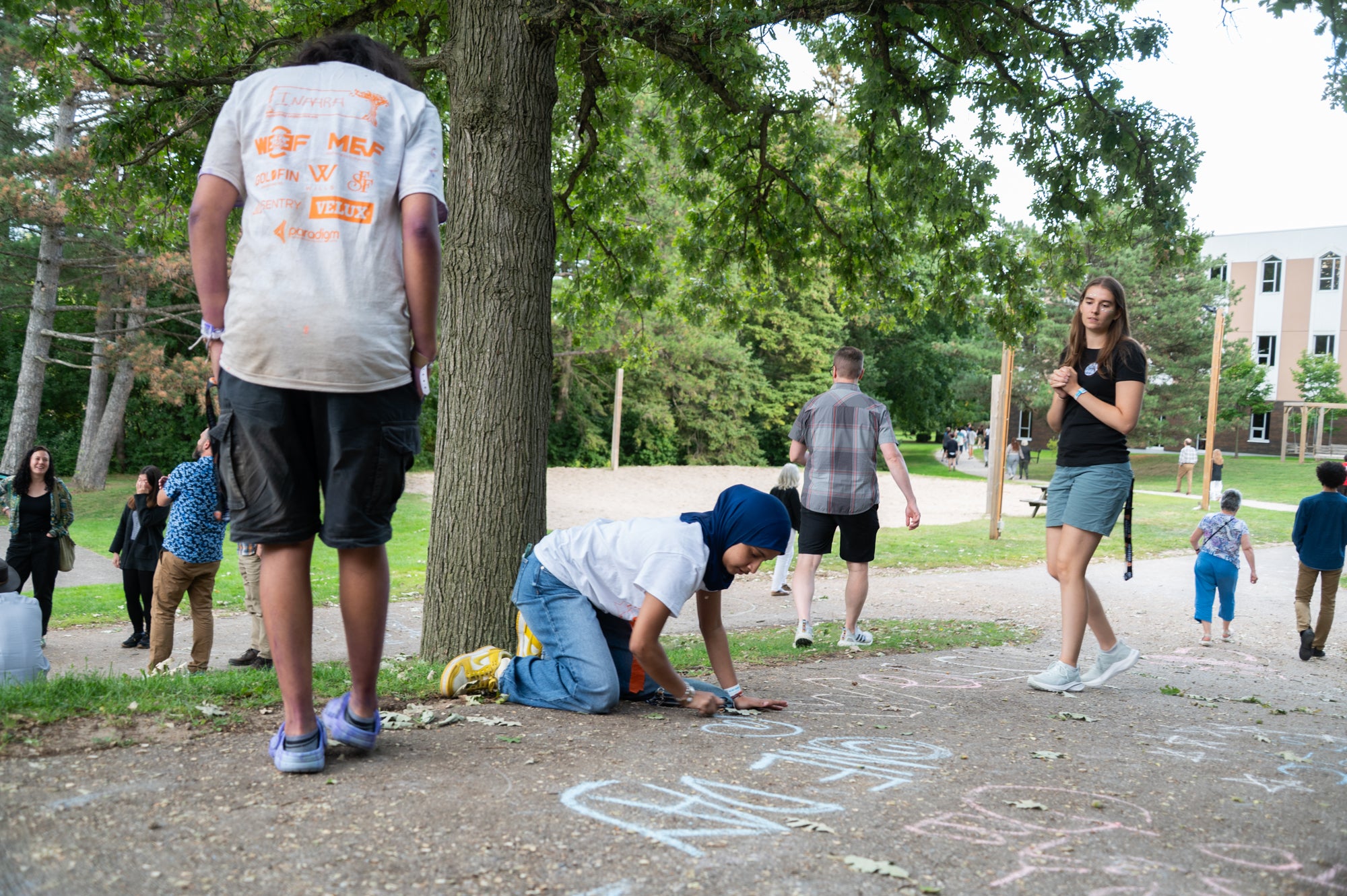 A student writes a positive note on the sidewalk with chalk