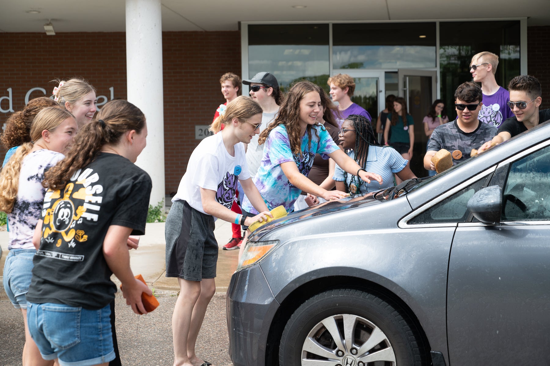 undregrad students help wash a car