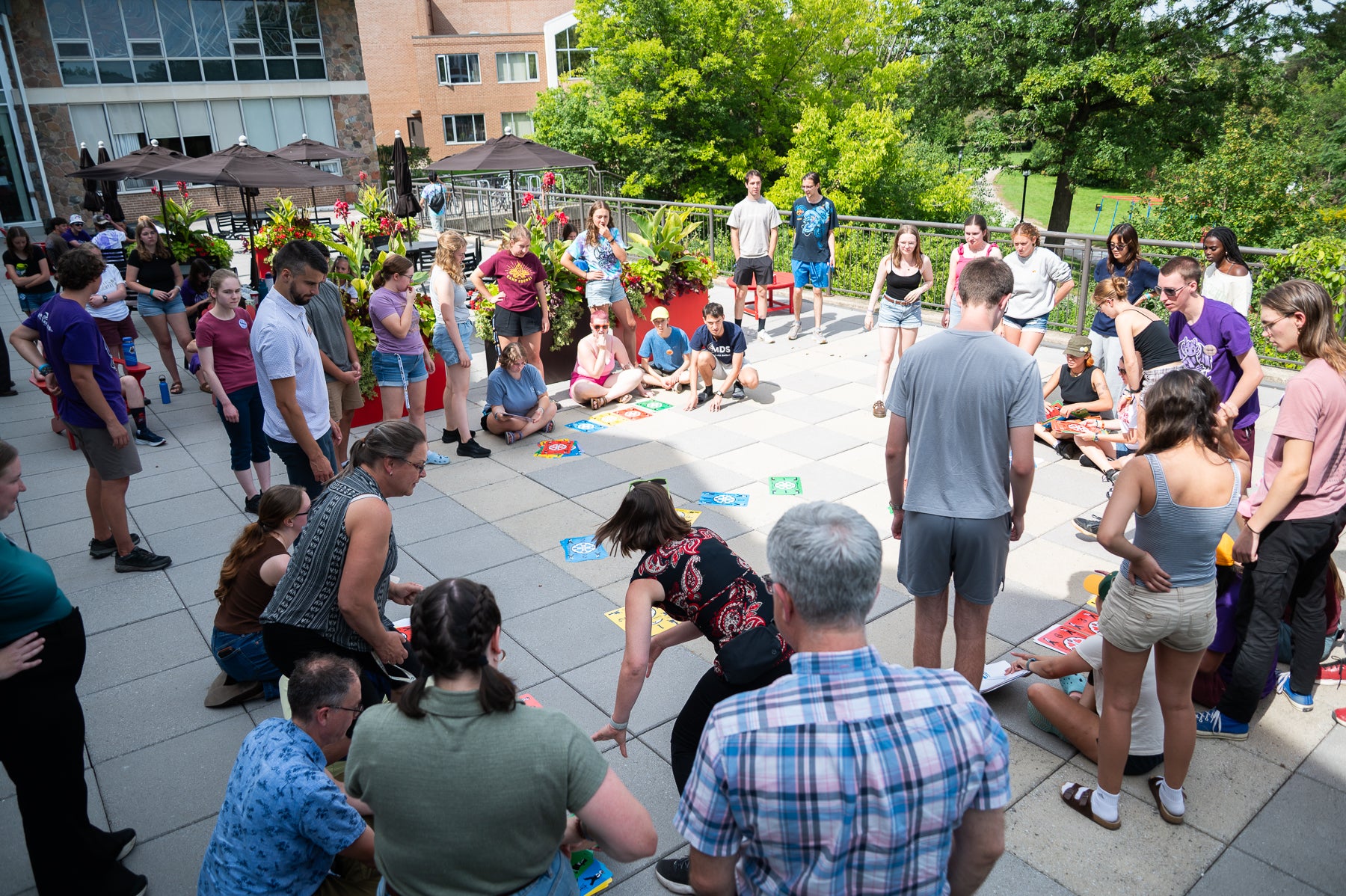 A crowd of students and staff play dutch blitz with oversized cards on the Grebel patio