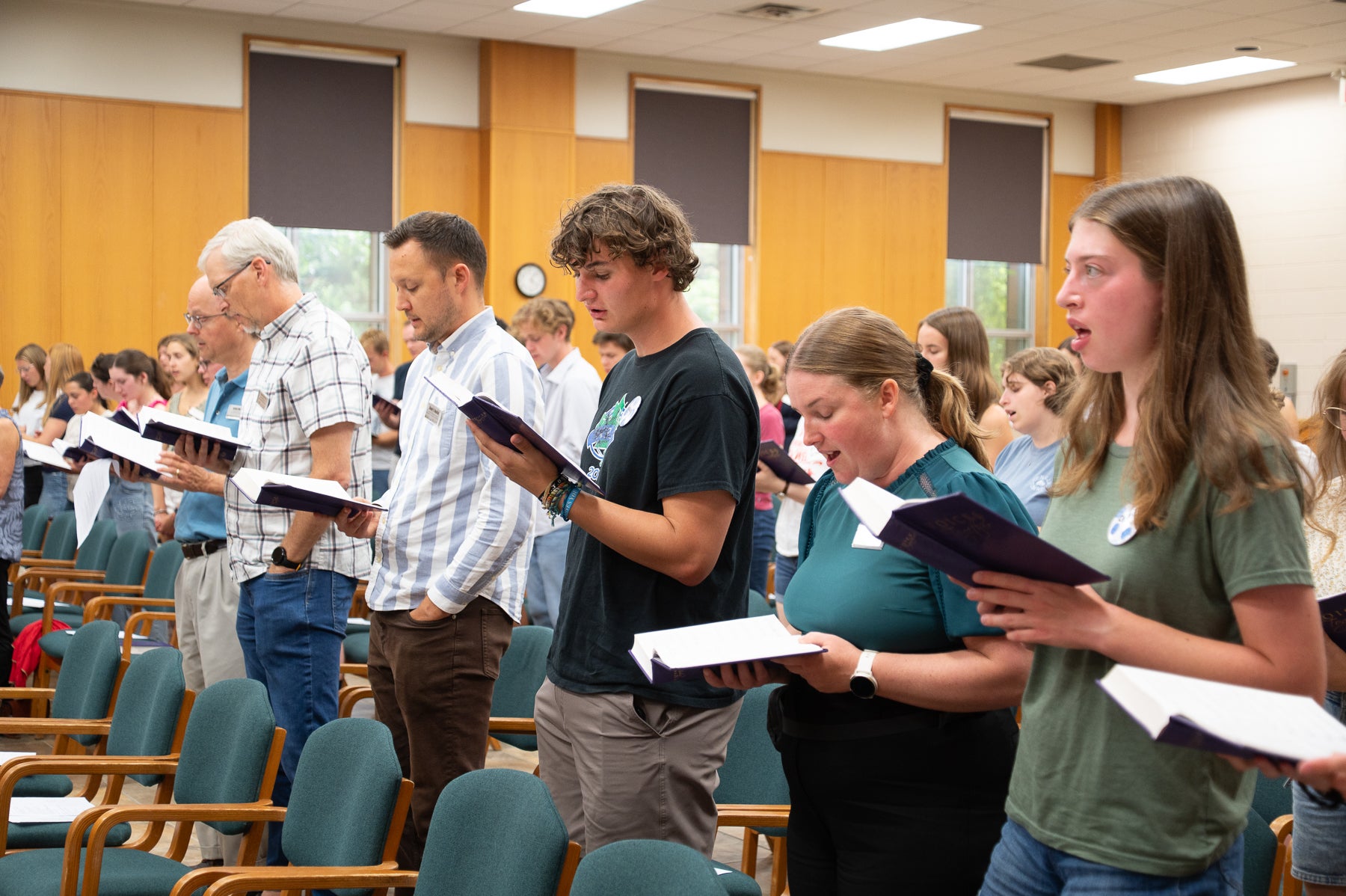 students and faculty sing from hymnals in the great hall