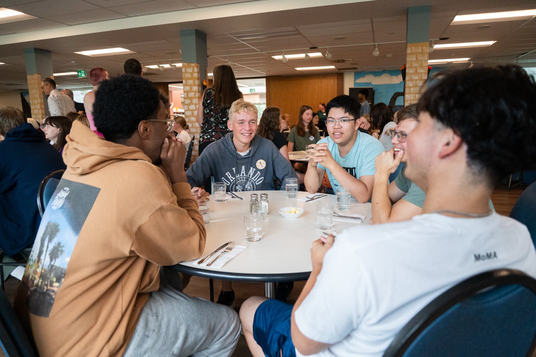 Students gather around a circle table in the dining room