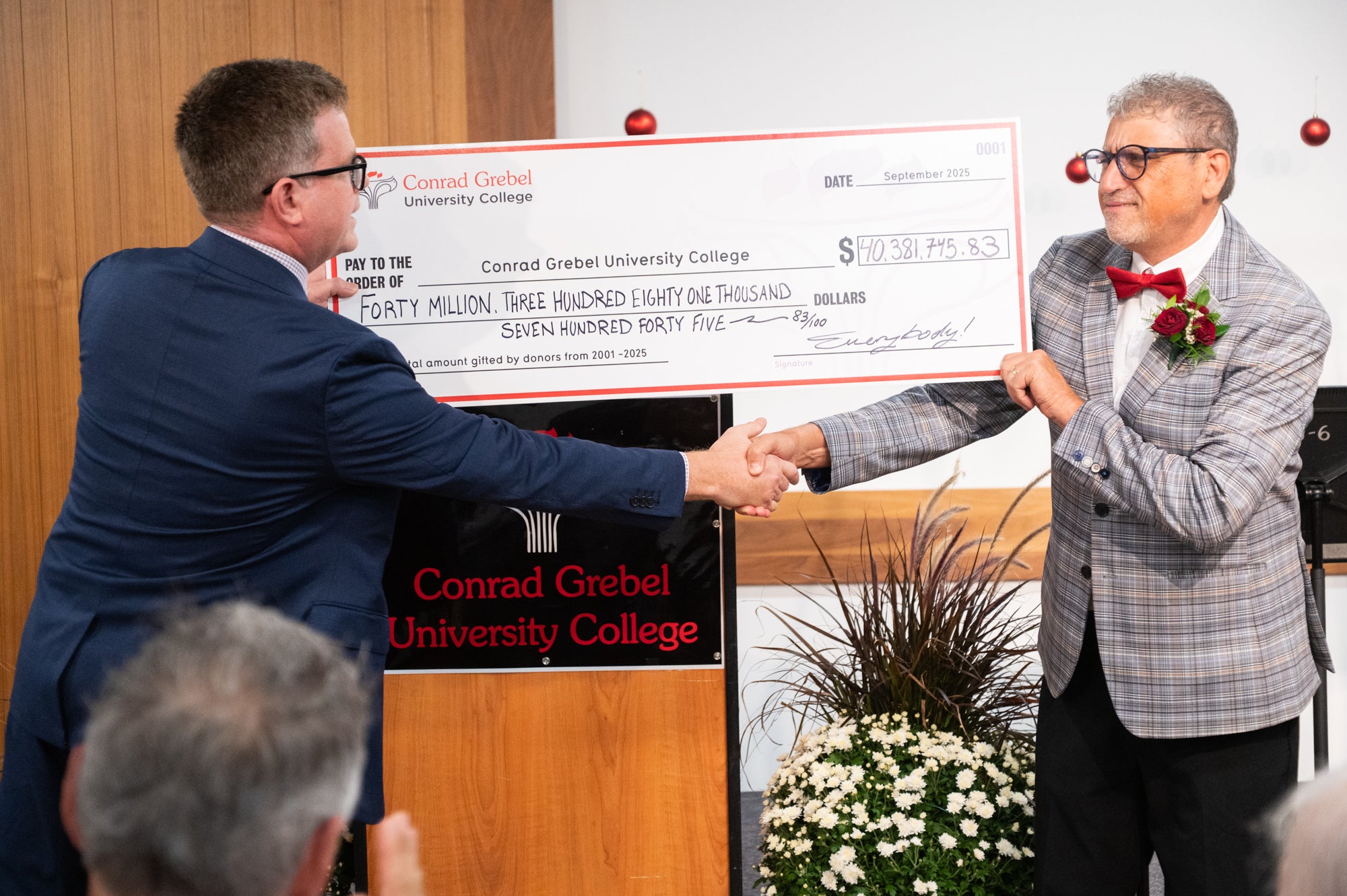 Fred shakes hands with Marcus, holding a novelty cheque