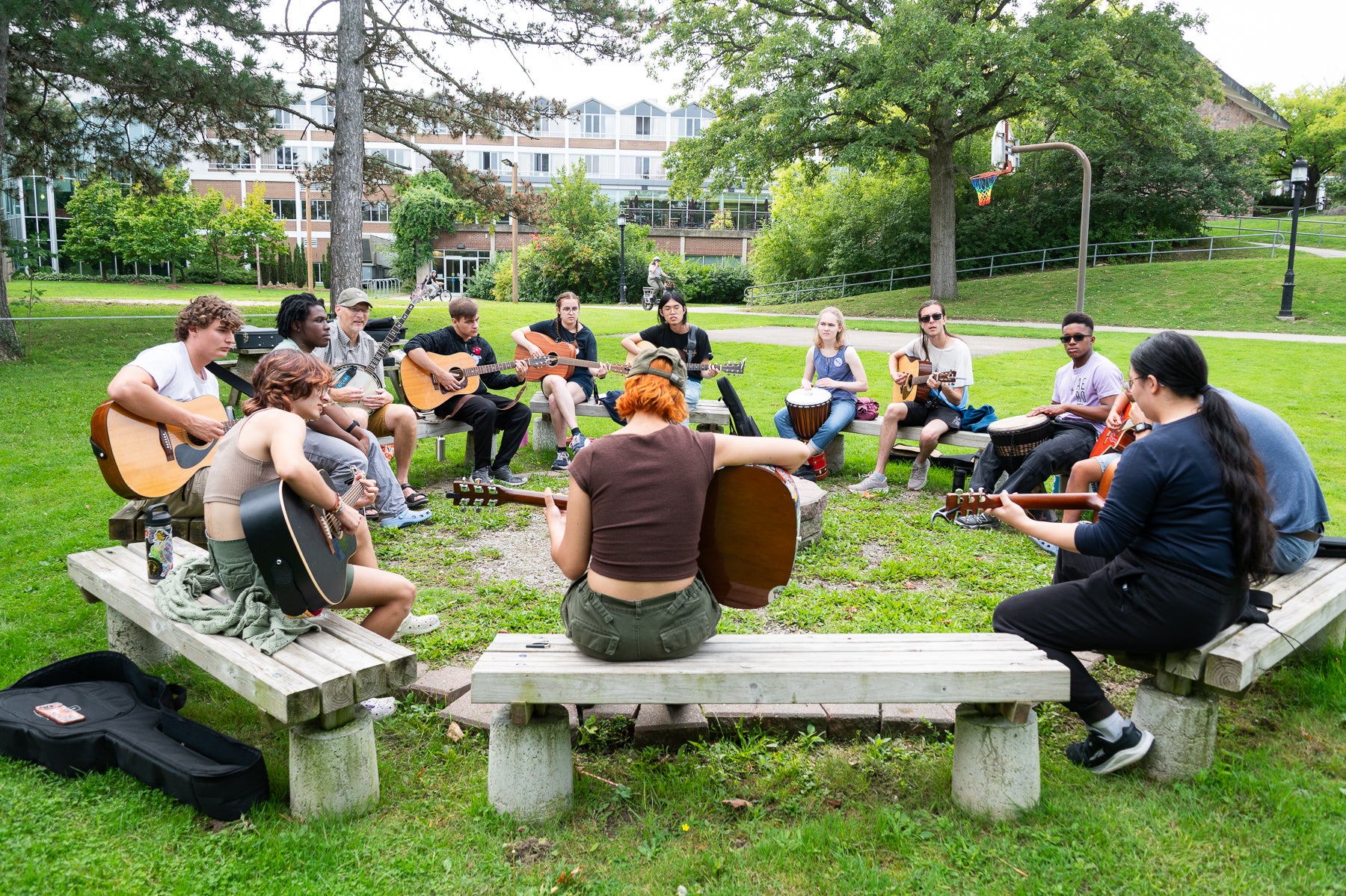 A group of students jam with guitars, drums, by the Grebel campfire