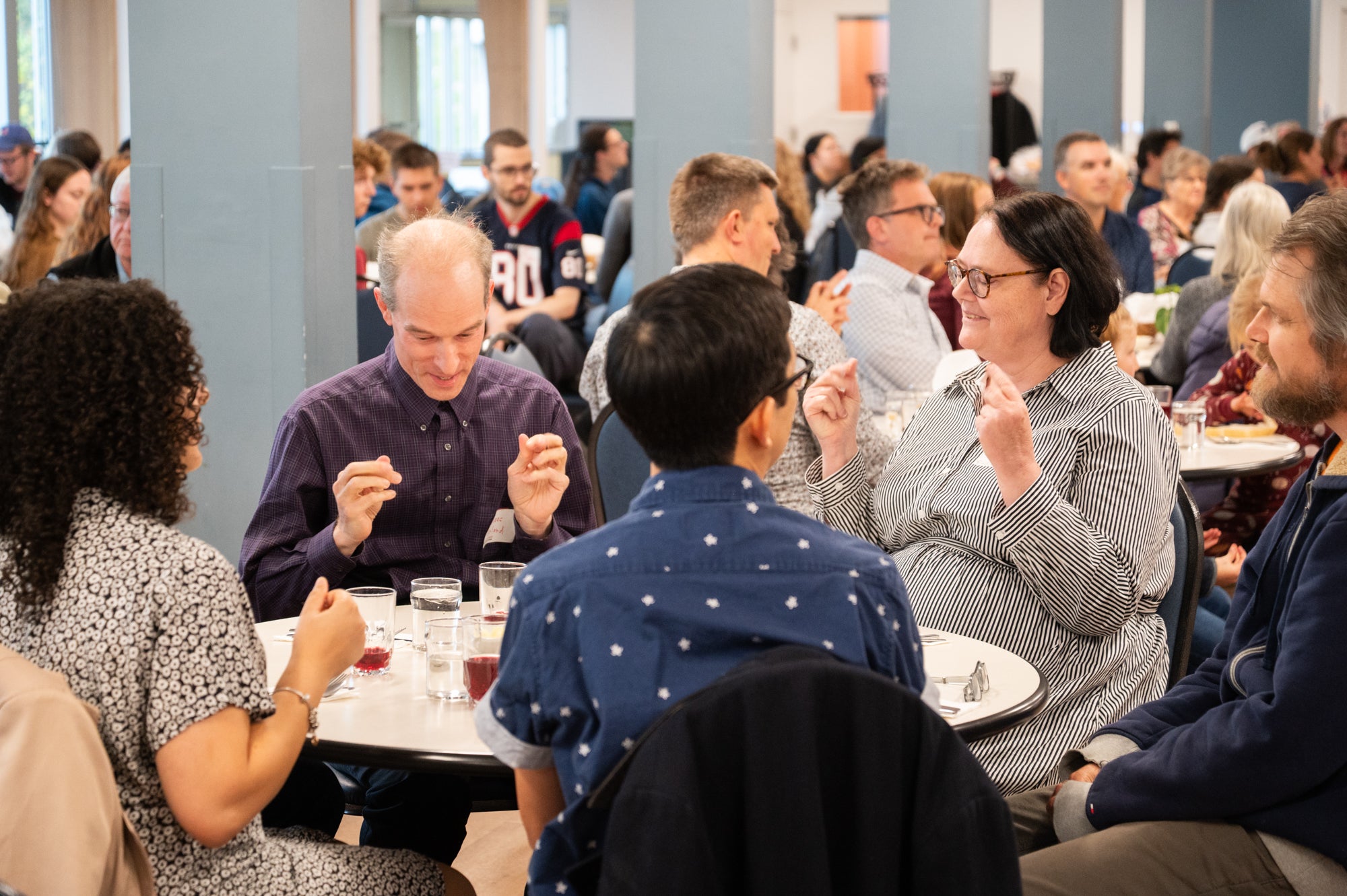 A group of adults sit together at a table in the Grebel dining room