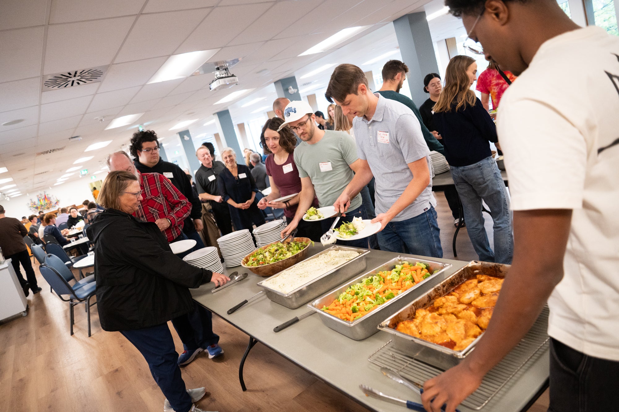 Dinner attendees help themselves to dinner from a buffet table