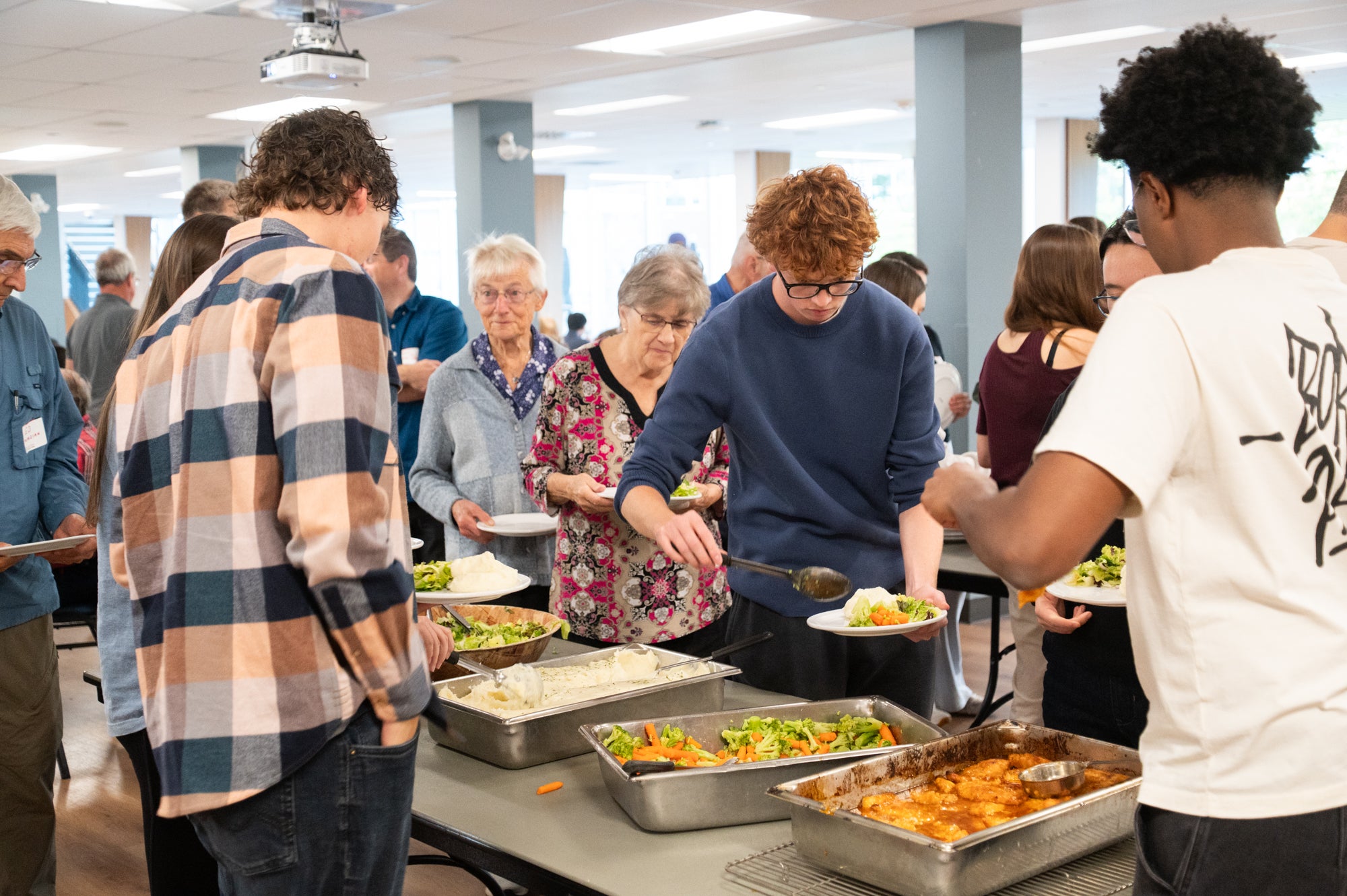 Dinner attendees help themselves to dinner from a buffet table