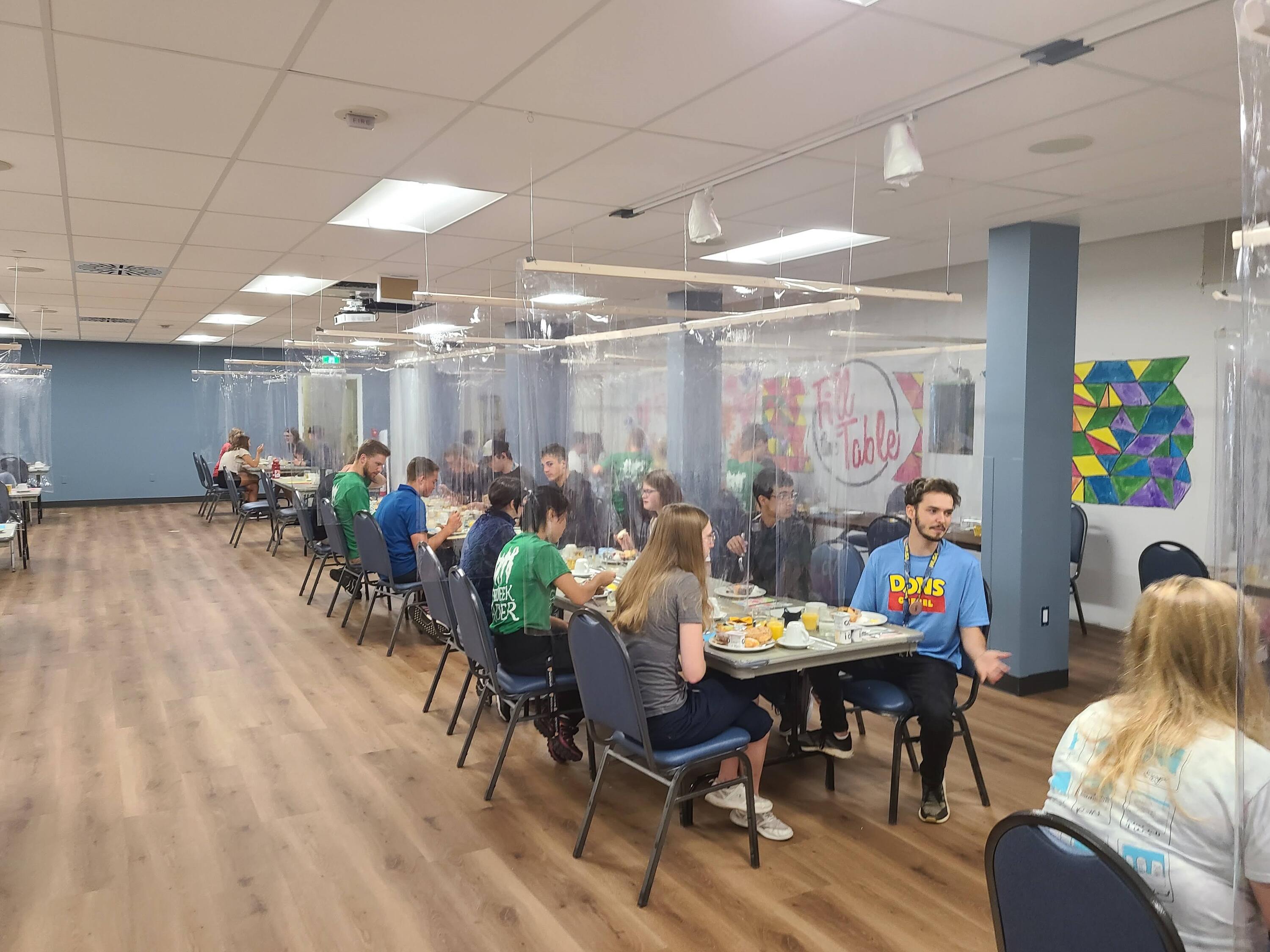 Students enjoy eating together in the new dining room, set up with plastic barriers for COVID prevention 