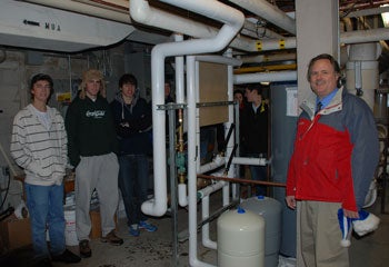 A group photo of Solar Grebel and Paul Penner under the pipes used for the solar panels.