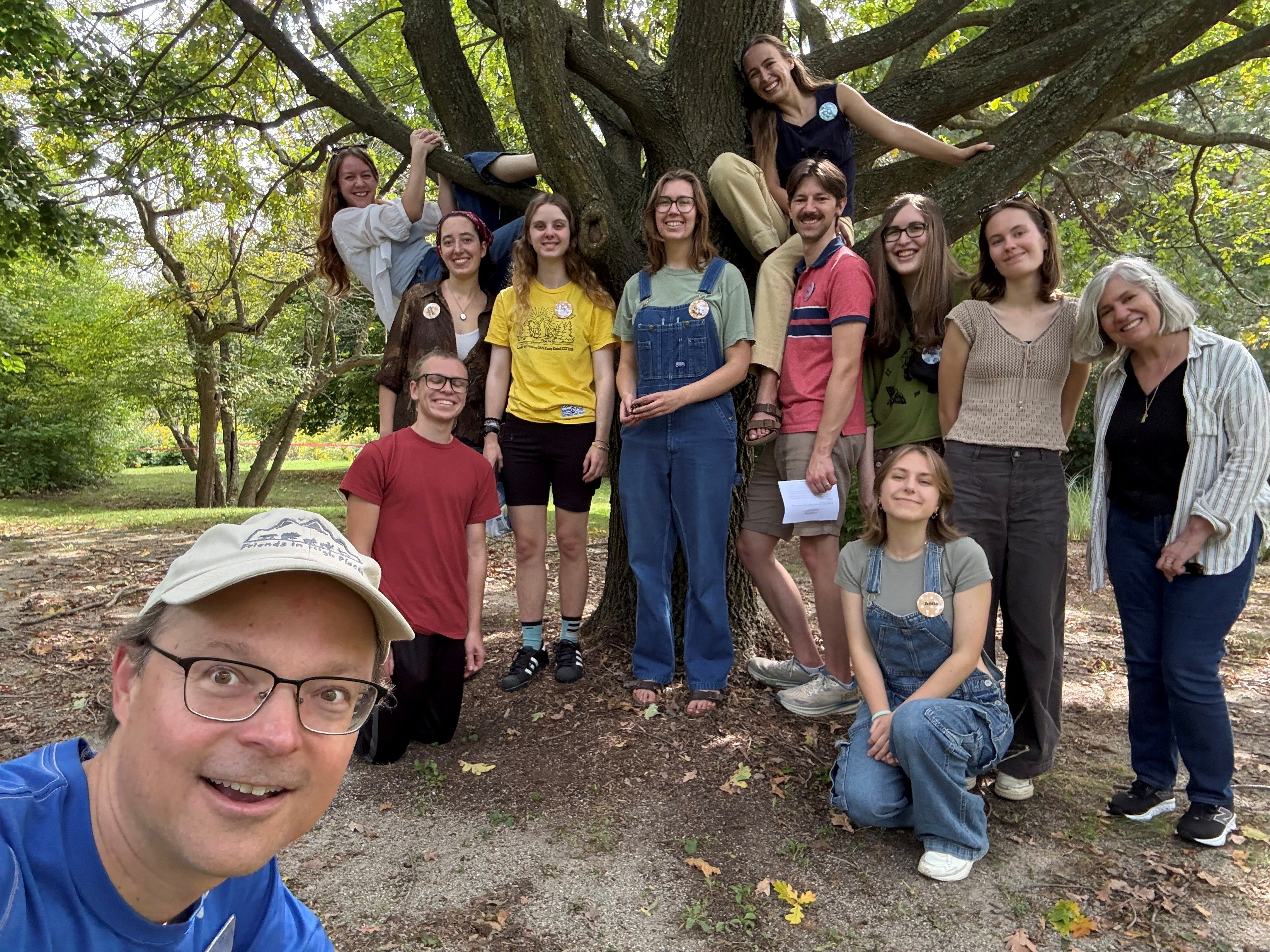 students and faculty pose for a photo in front of an oak tree