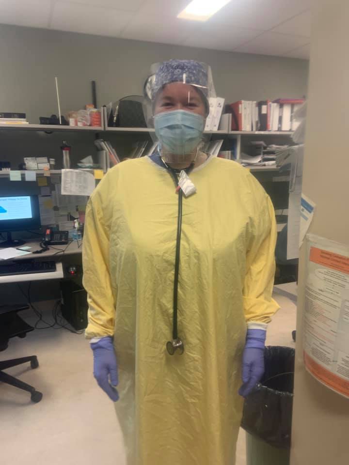 Brenda is photographed in a nursing station wearing yellow protective gowns with a face mask, goggles and gloves. 
