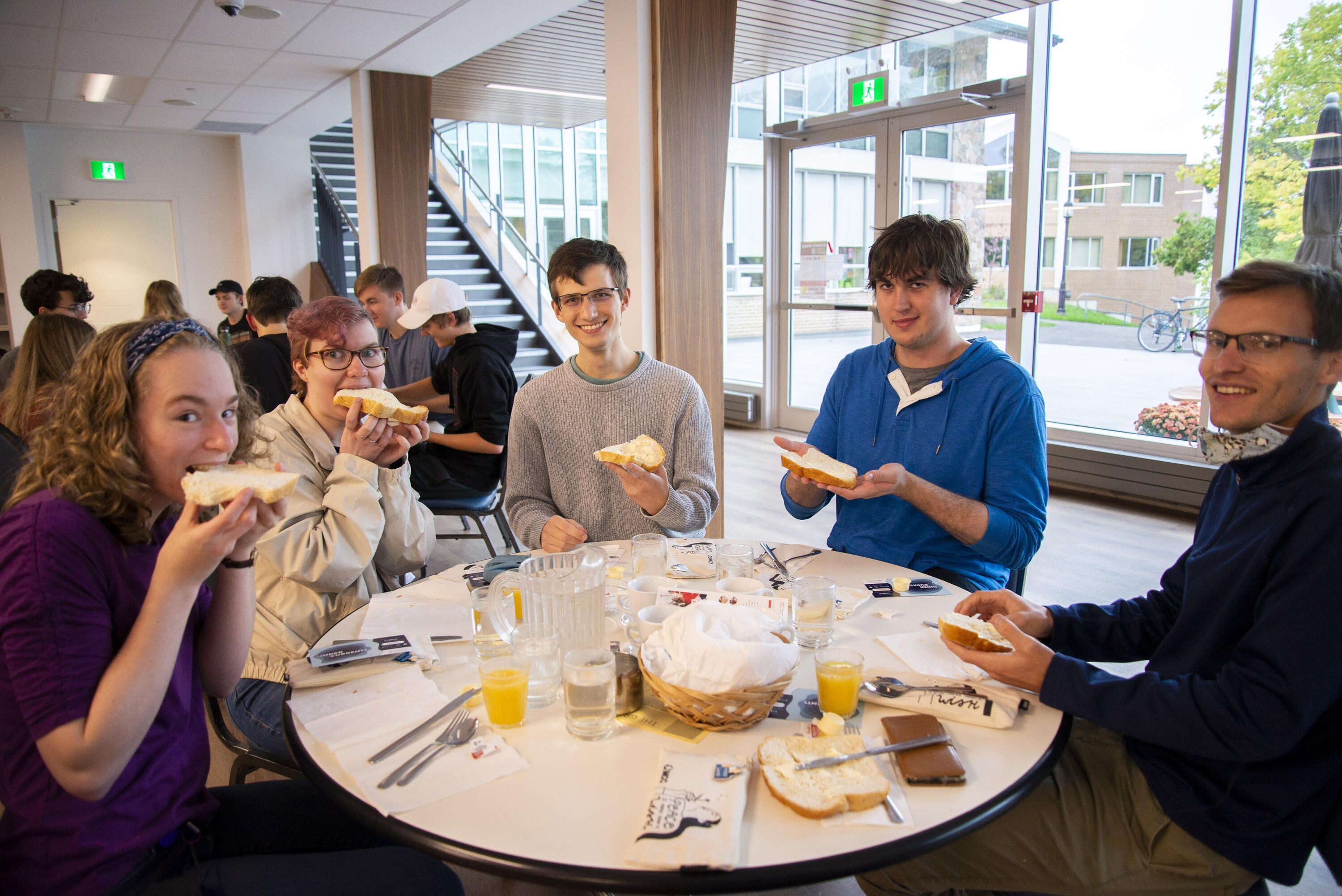 students eating bread sitting aorund a table