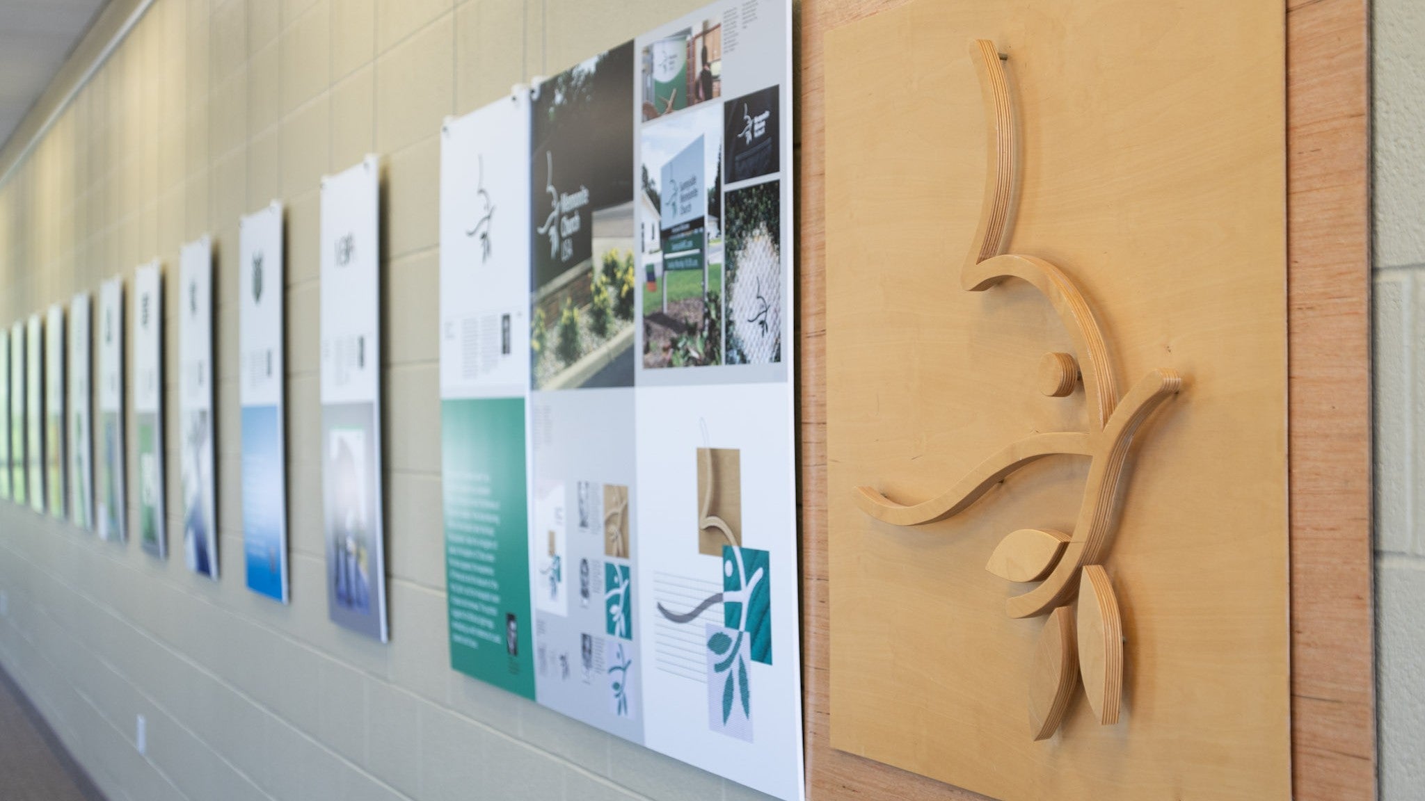 LIbrary wall with displays featuring Geln's designs, plus a wooden cut out of the MCEC dove logo