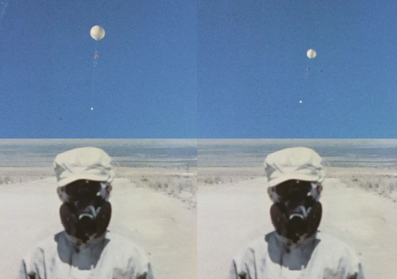A screen shot of a film. A person in a white hazmat suit stands in a white, flat landscape. The blue sky takes up the upper half of the image, where a large weather balloon floats. 