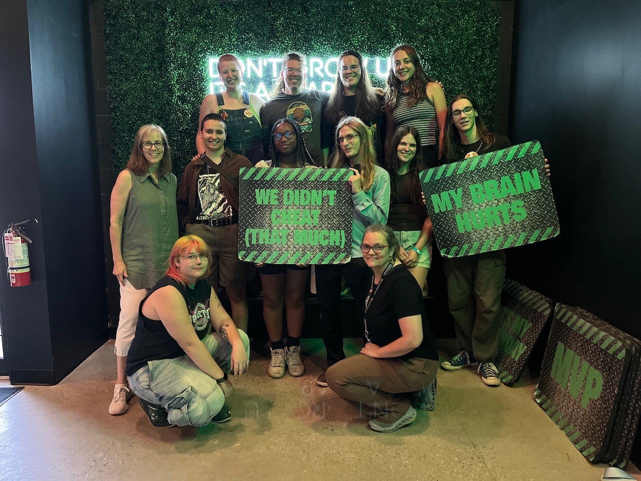 students and faculty pose with silly signs after completing an escape room