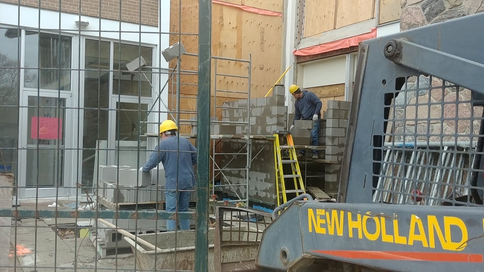 workers lay cinder blocks for the elevator shaft. 