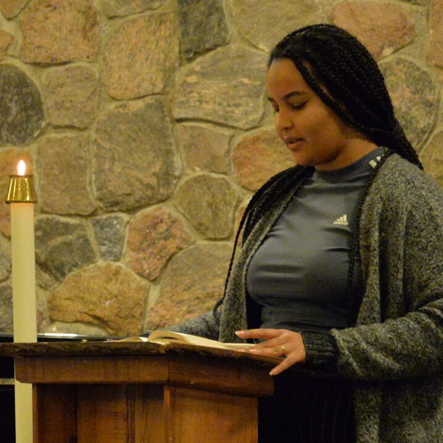 student sppeaks at a pulpit in chapel with a lit candle nearby