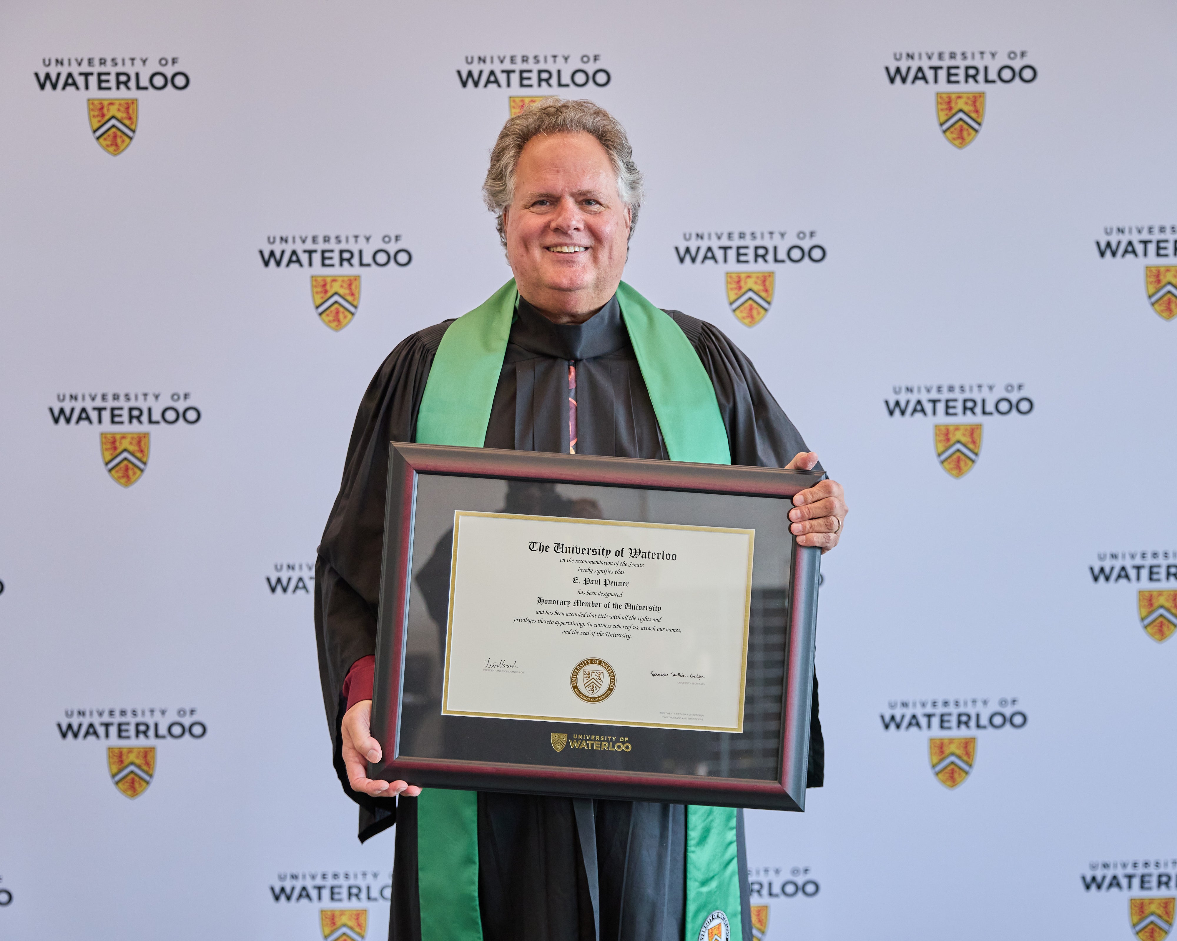 Paul Penner posing with honorary degree from the University of Waterloo
