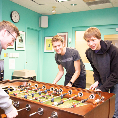 three students play foosball in the games lounge