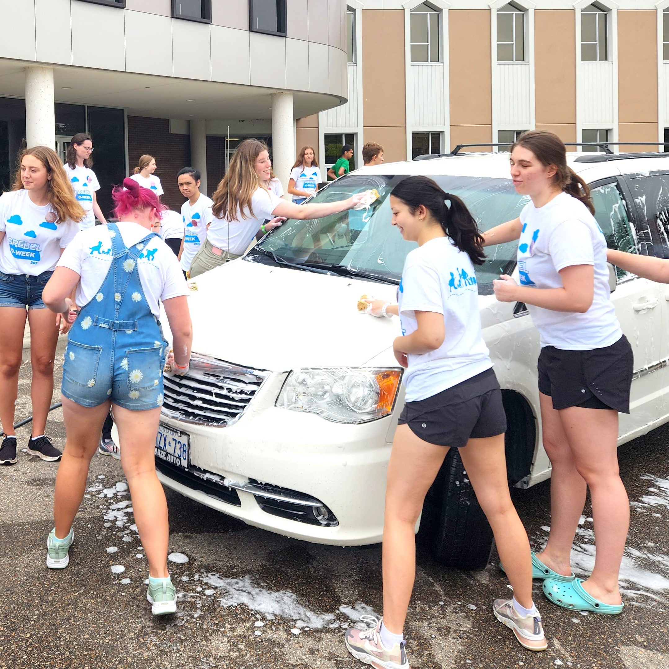 Grebel students washing a white mini van outside 
