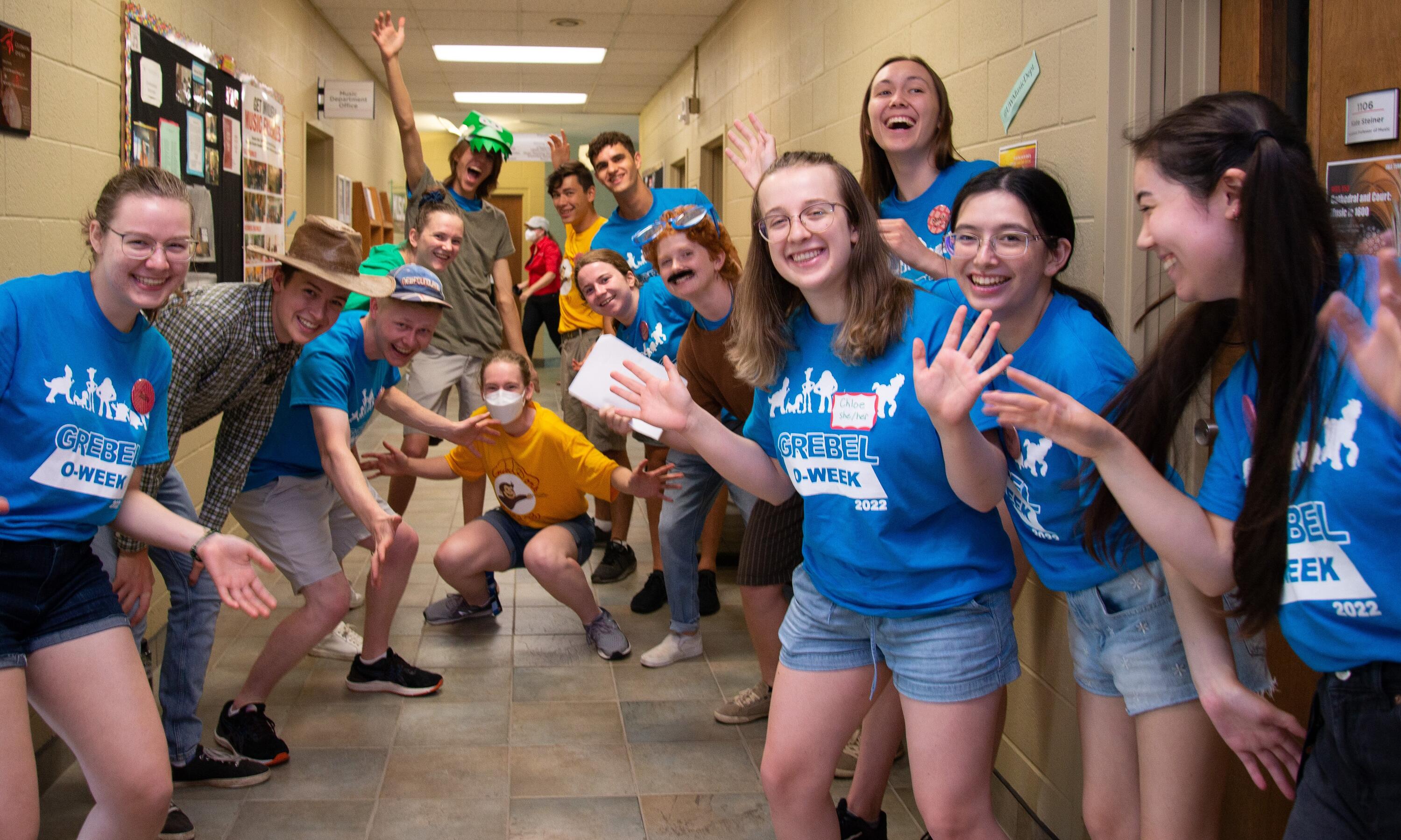 students in blue Grebel shirts welcoming students to the dorm hallway 