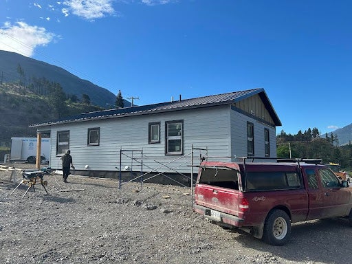 A long house and a red truck with mountains in the background