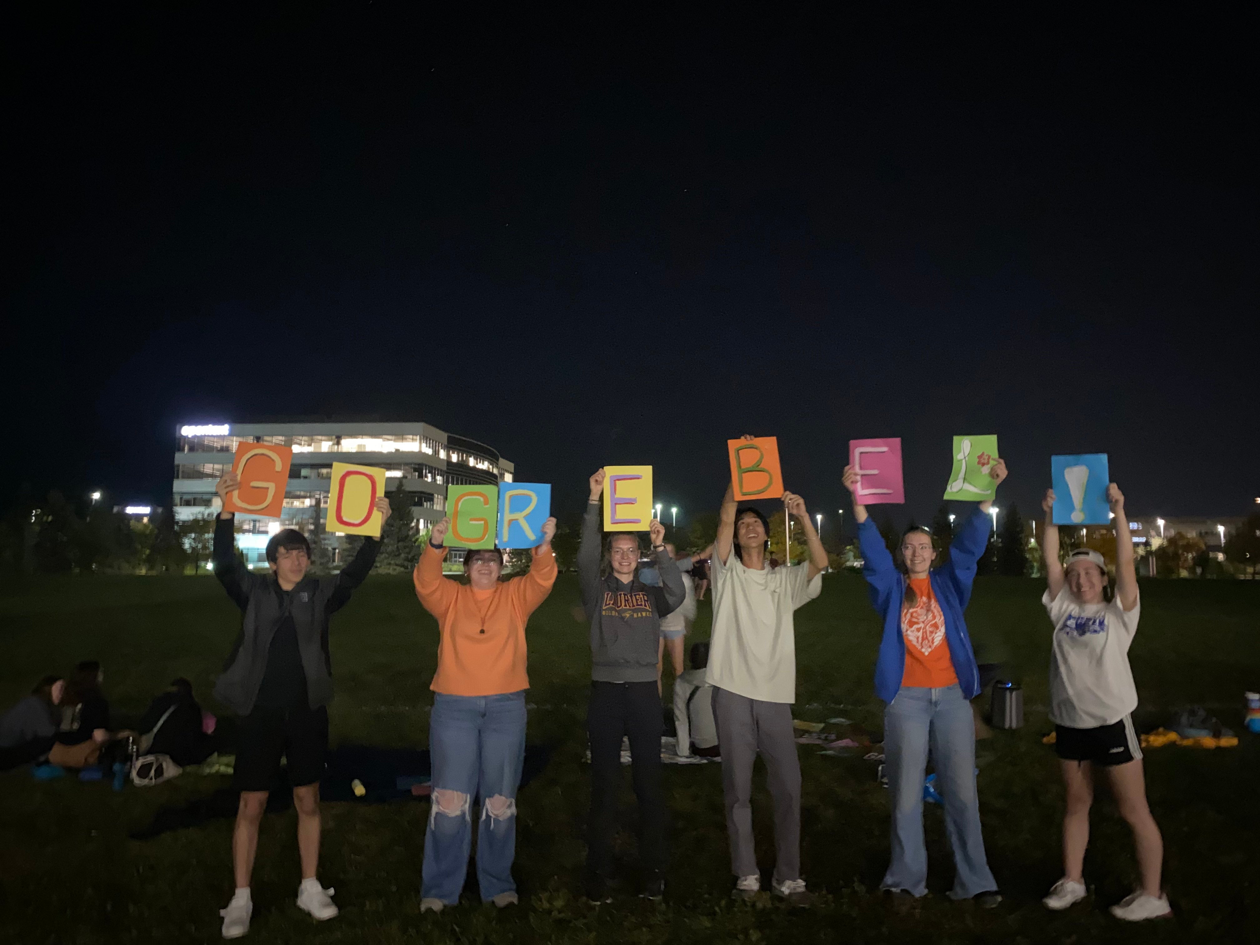 students holding signs that spell out Go Grebel!