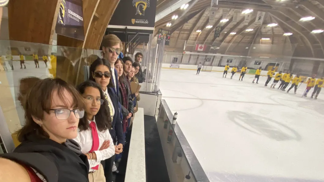 Students lined up in the stands of a hockey rink 