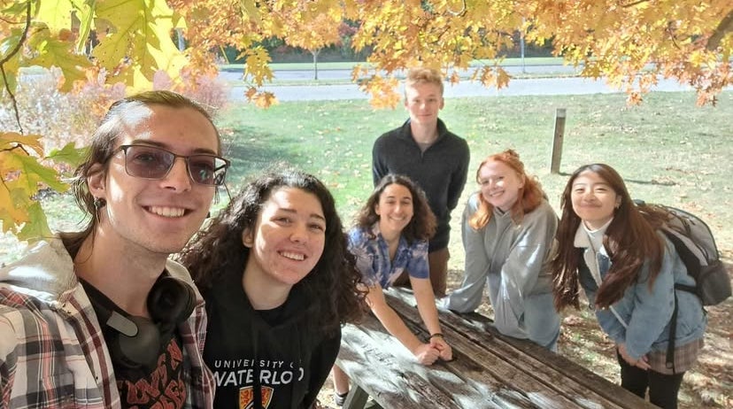 A group selfie with students at a picnic table in the fall