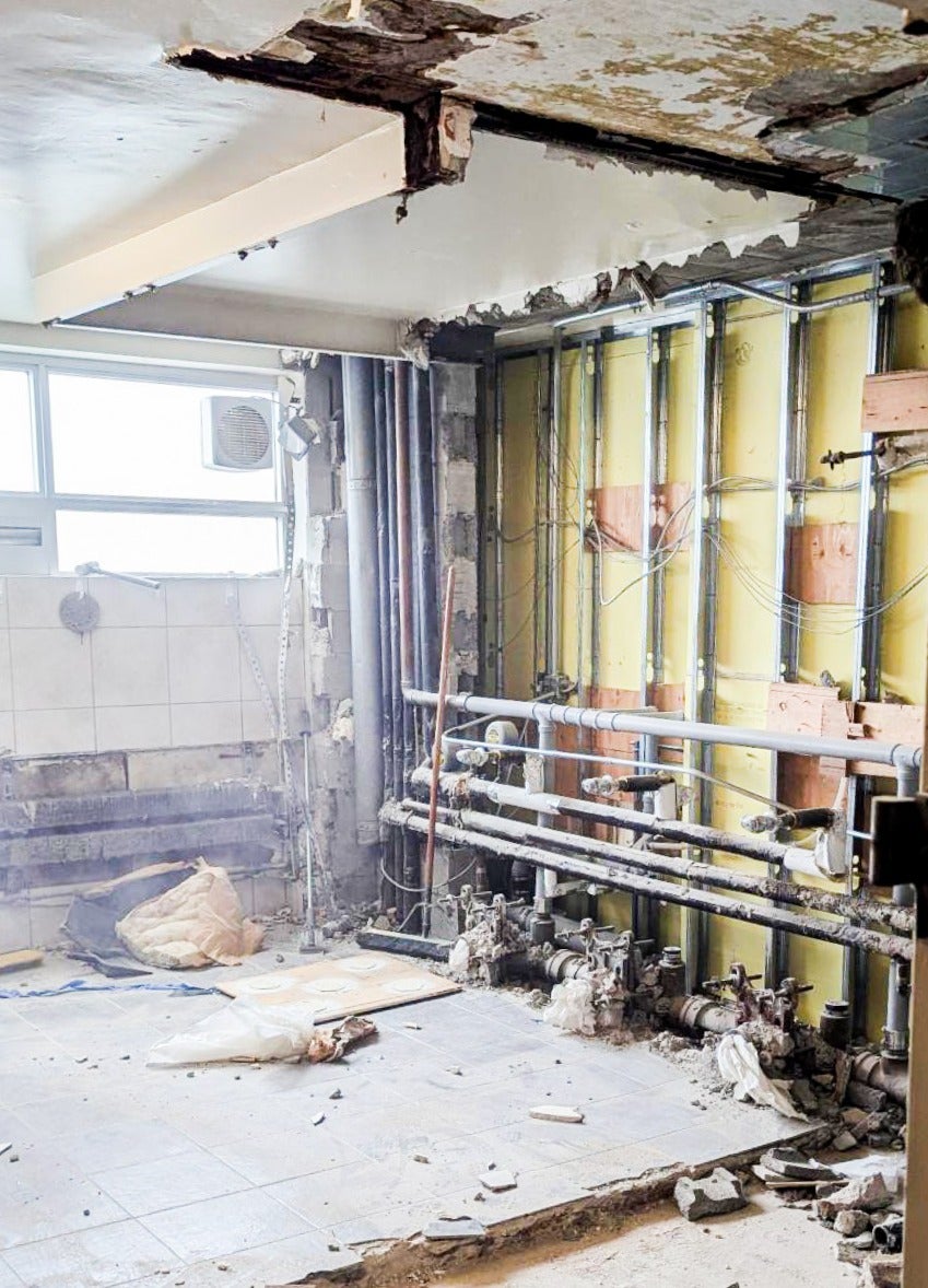 bathroom in the middle of renovations, exposed piping, toilets and sinks removed 