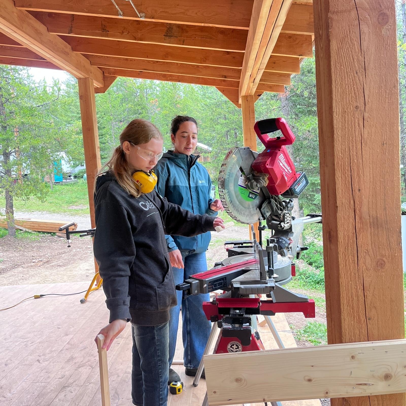 Mona and another volunteer using a power saw on site