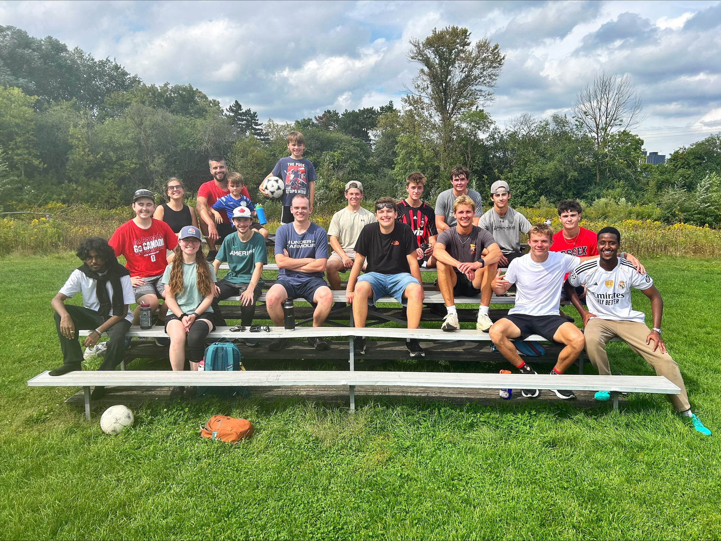 Studens sit on an elevated sitting area by the park soccer field