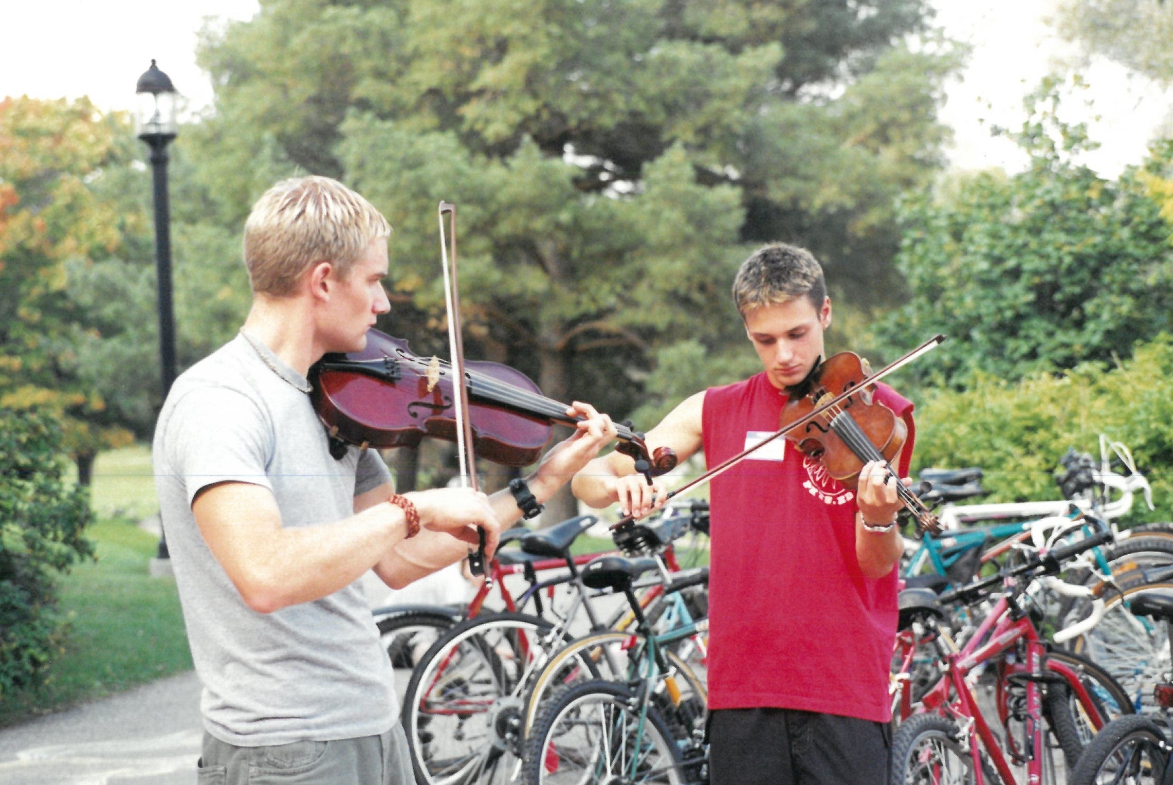 Two guys playing the violin outside