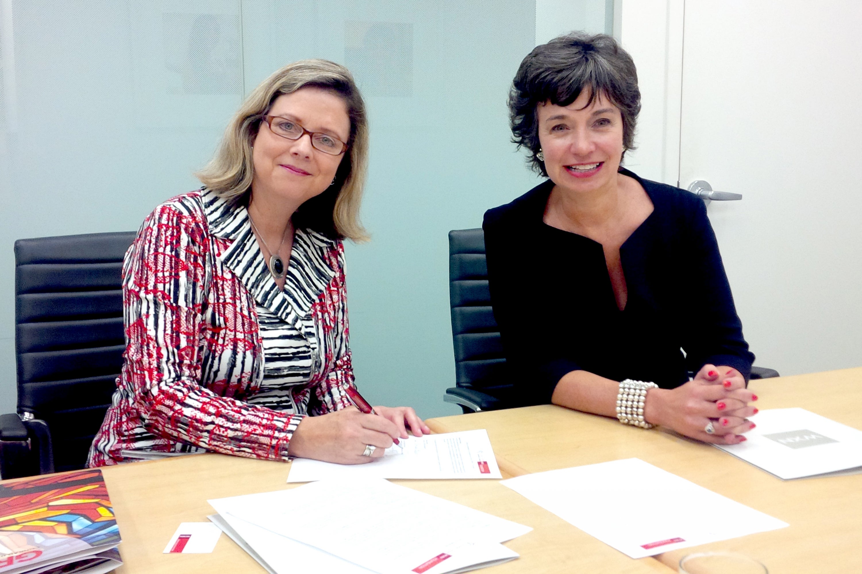 Susan Schultz Huxman and Pamela Jeffery sign an agreement