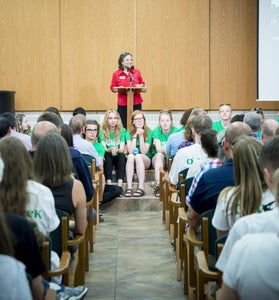 Mary Brubaker-Zehr standing in front of new students making a speech