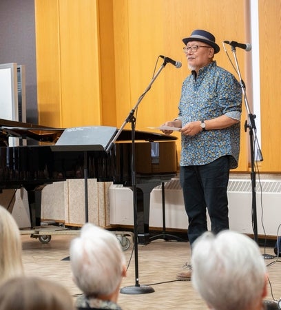 Dr. Tom Lee standing at microphone beside piano 