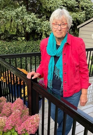 Marianne Enns holding onto railing posing in garden