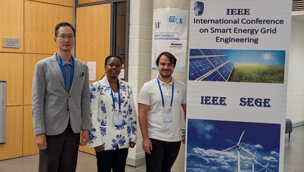 conference attendees posing before a flyer