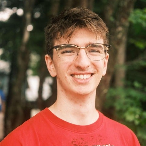 A male student wears a red T shirt and smiles