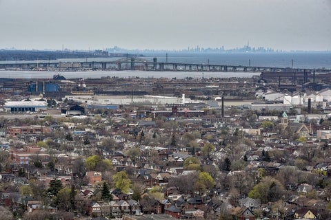 Skyline of residential houses looking towards Toronto across the lake, grey day, trees in early spring bloom with sparse light green leaves