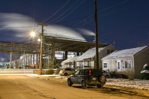 night shot of bungalows in front of steel plant, vapour clouds streaked across sky